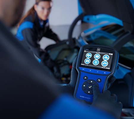 Técnico de servicio certificado de Cadillac usando una herramienta de diagnóstico de desempeño en un vehículo