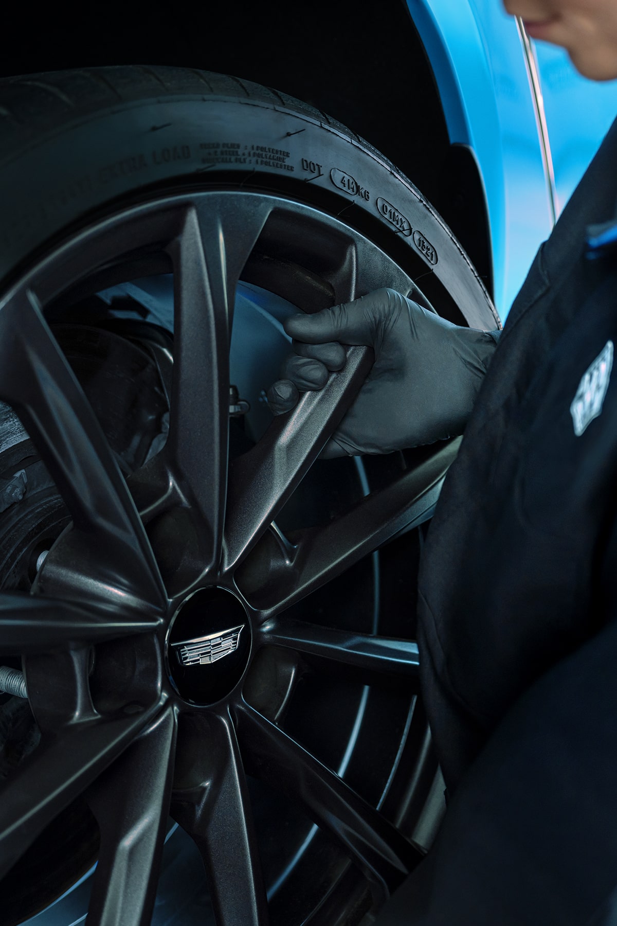 Técnico de servicio certificado de Cadillac instalando un rin nuevo en un vehículo