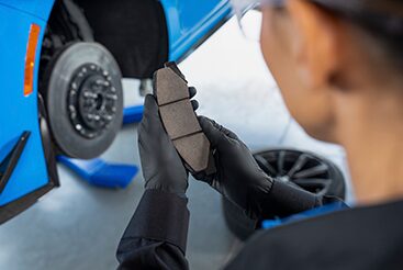 Cadillac Technician Standing Next to a Vehicle Inspecting a Brake Pad