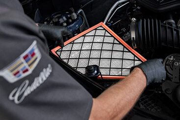 Cadillac Certified Service Technician inspecting an engine air filter