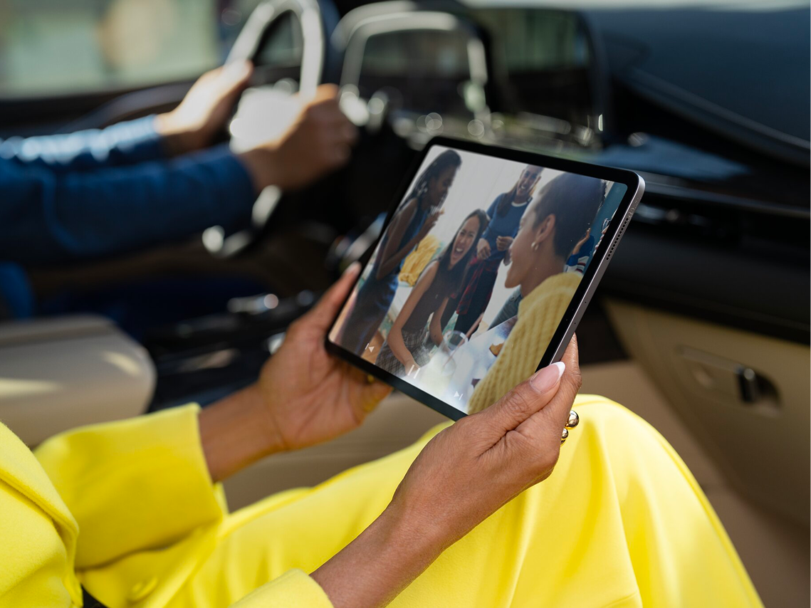 Close-up of a Front Row Passenger Holding and Watching an iPad in a Cadillac
