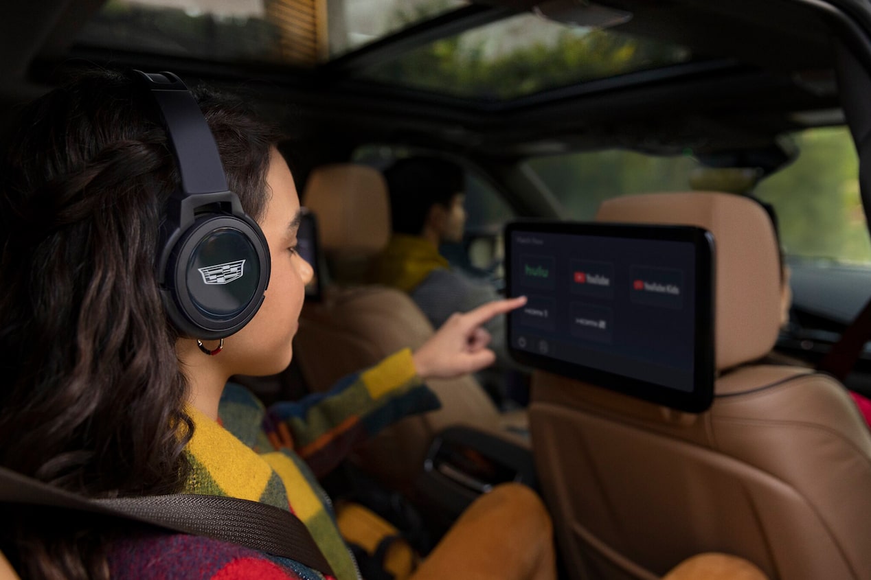 A Girl in the Second Row of a Cadillac Choosing an Entertainment Option on the Headrest Display Screen 