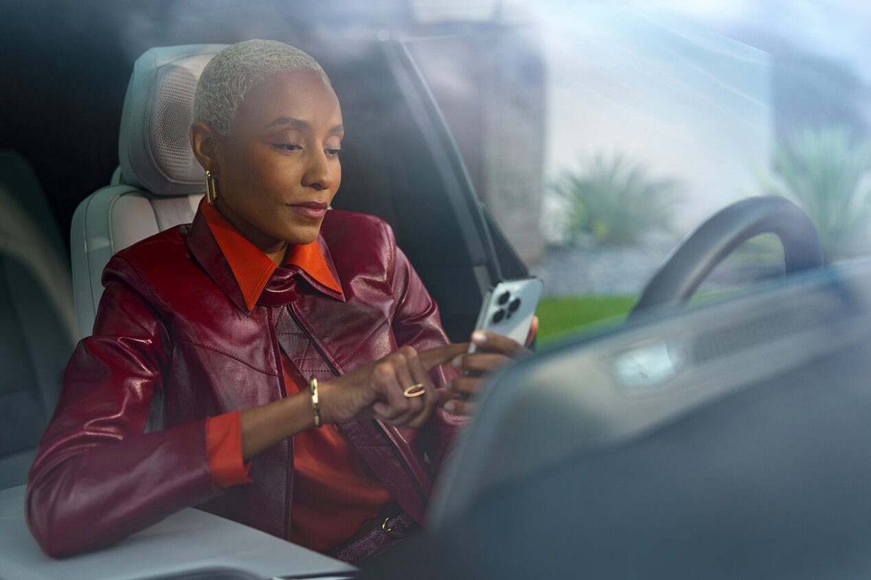 Una mujer en el asiento del conductor utiliza los comandos remotos de OnStar a través de su smartphone