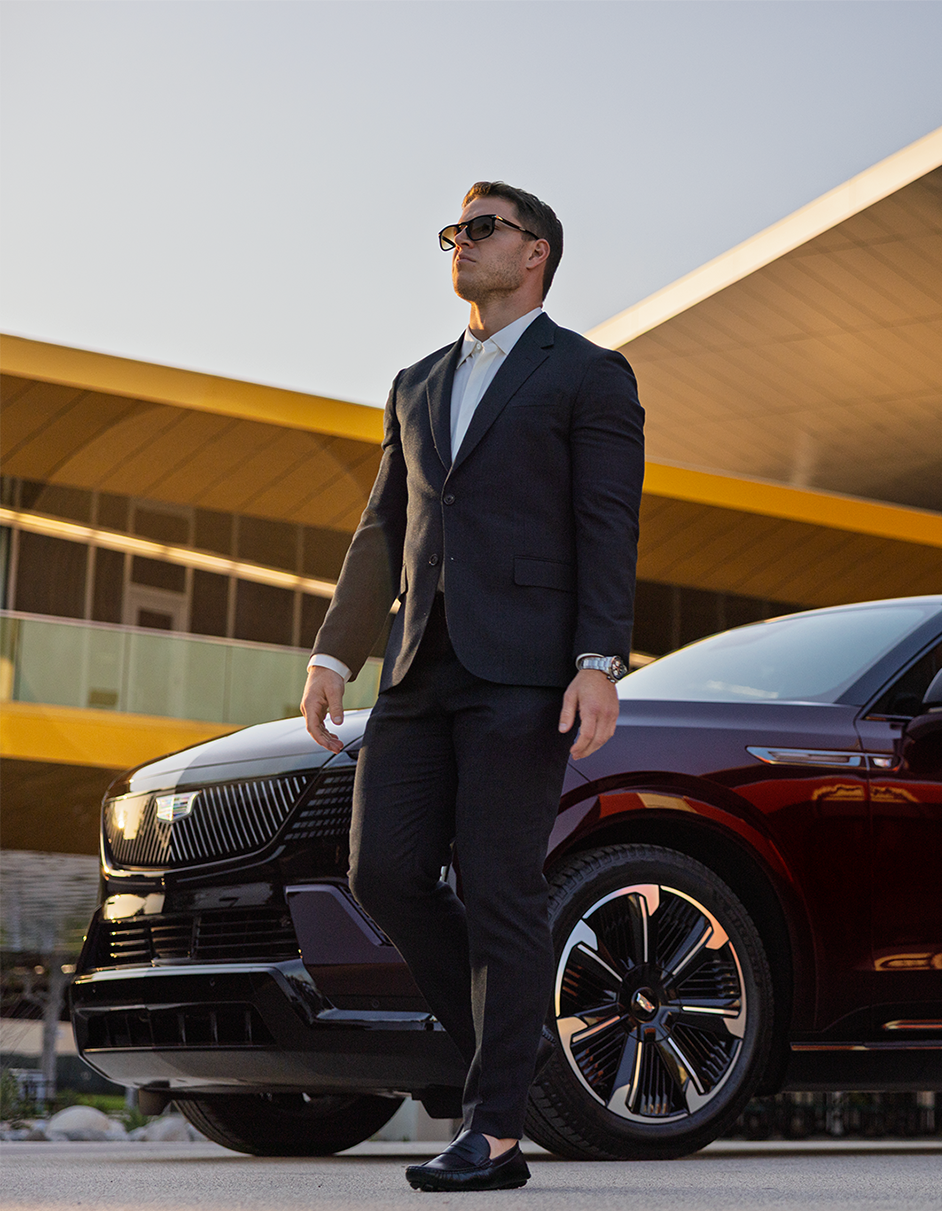 Christian McCaffrey in a Suit Standing Beside a Cadillac Vehicle