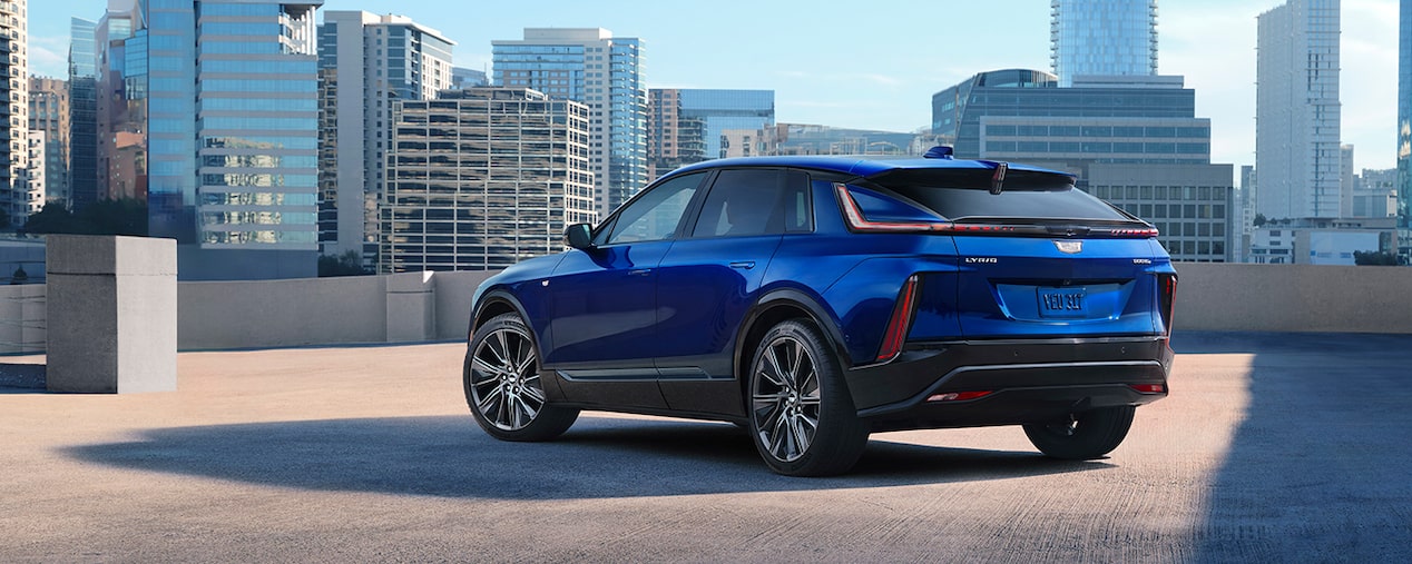 Three-Quarter Rear View of a Blue 2025 Cadillac LYRIQ Parked Overlooking the City Skyscrapers
