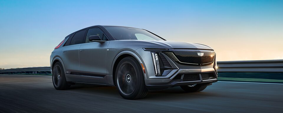 Low Angle Three Quarters View of a Silver Cadillac Vehicle Driving Down the Highway