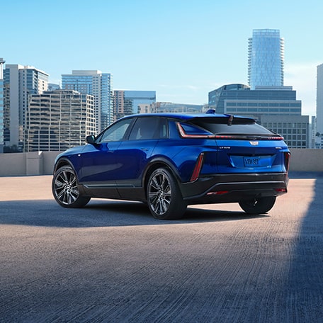 Three-Quarter Rear View of a Blue 2025 Cadillac LYRIQ Parked Overlooking the City Skyscrapers