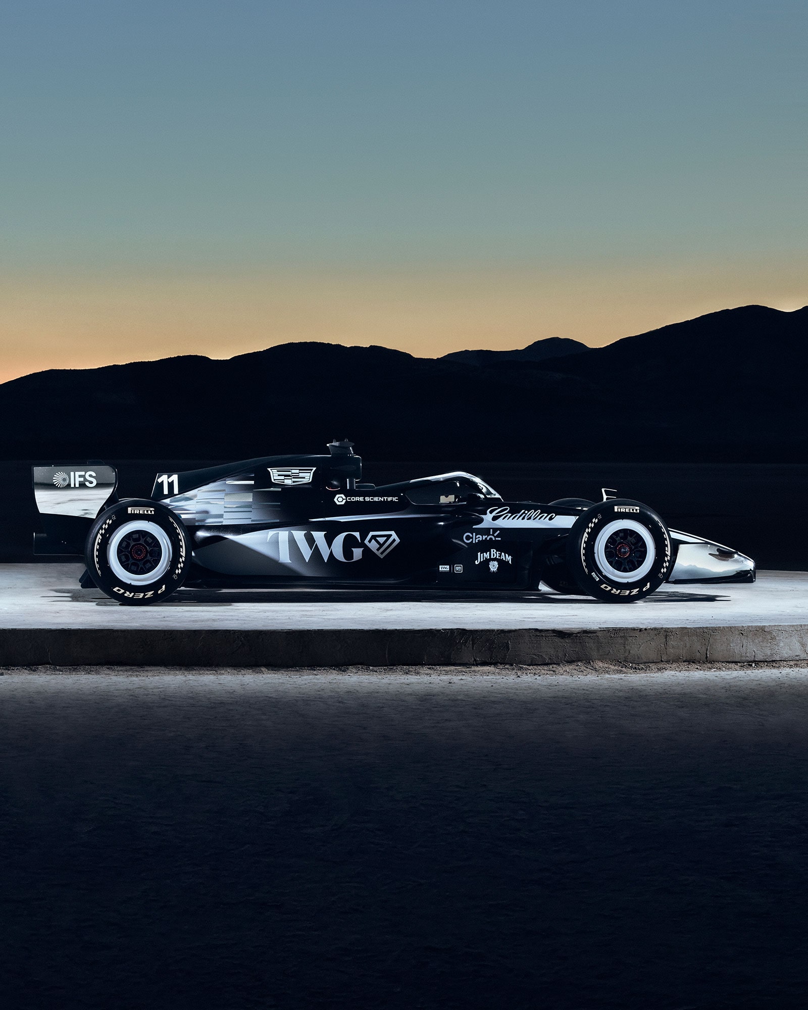 Two Cadillac Racing Cars Facing Outwards on a Circular Structure Outside in the Evening.
