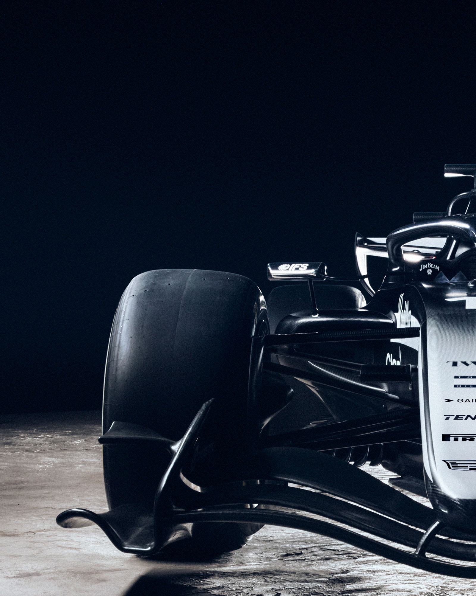 A Low Front View Of A Cadillac-Branded Formula Race Car Illuminated Dramatically Against a Dark Desert Landscape.
