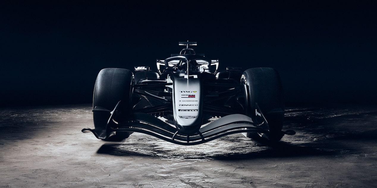 A Low Front View Of A Cadillac-Branded Formula Race Car Illuminated Dramatically Against a Dark Desert Landscape.