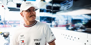Valtteri Bottas Wearing A White Cadillac Formula 1 Team Cap, Standing Beside Wall With Cadillac Logo.