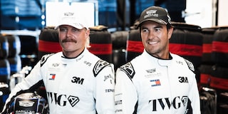 Valtteri Bottas And Sergio "Checo" Perez Posing For Photo While Wearing White Firesuits In Team Garage.