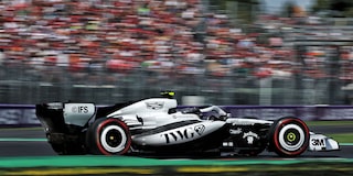 Open-Wheel F1 Cadillac Race Car Speeds Down Racetrack During Practice Session. Motion Blur Of Crowd In The Background.