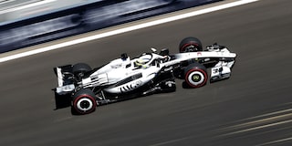 El auto de carrera Cadillac F1 de rines descubiertos avanza a toda velocidad por la pista durante la sesión de clasificación. Desenfoque de movimiento de la multitud en el fondo.