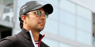 Cadillac F1 Team Driver Checo Perez Standing in Front of a Glass Building