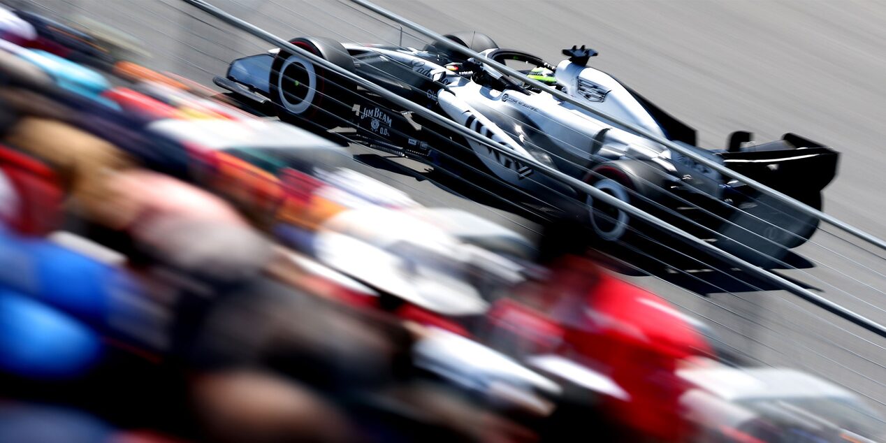 A Cadillac F1 Race Car Speeding Along a Racetrack Past Grandstands