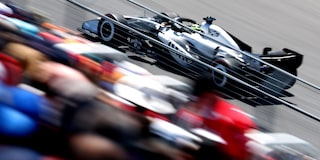 A Cadillac F1 Race Car Speeding Along a Racetrack Past Grandstands