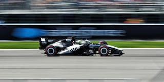 A Cadillac F1 Race Car Speeding Along a Track With Grandstands in the Background