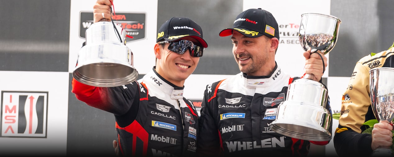 Two Cadillac Race Car Drivers Holding Grand Prix of Long Beach Trophies and Smiling