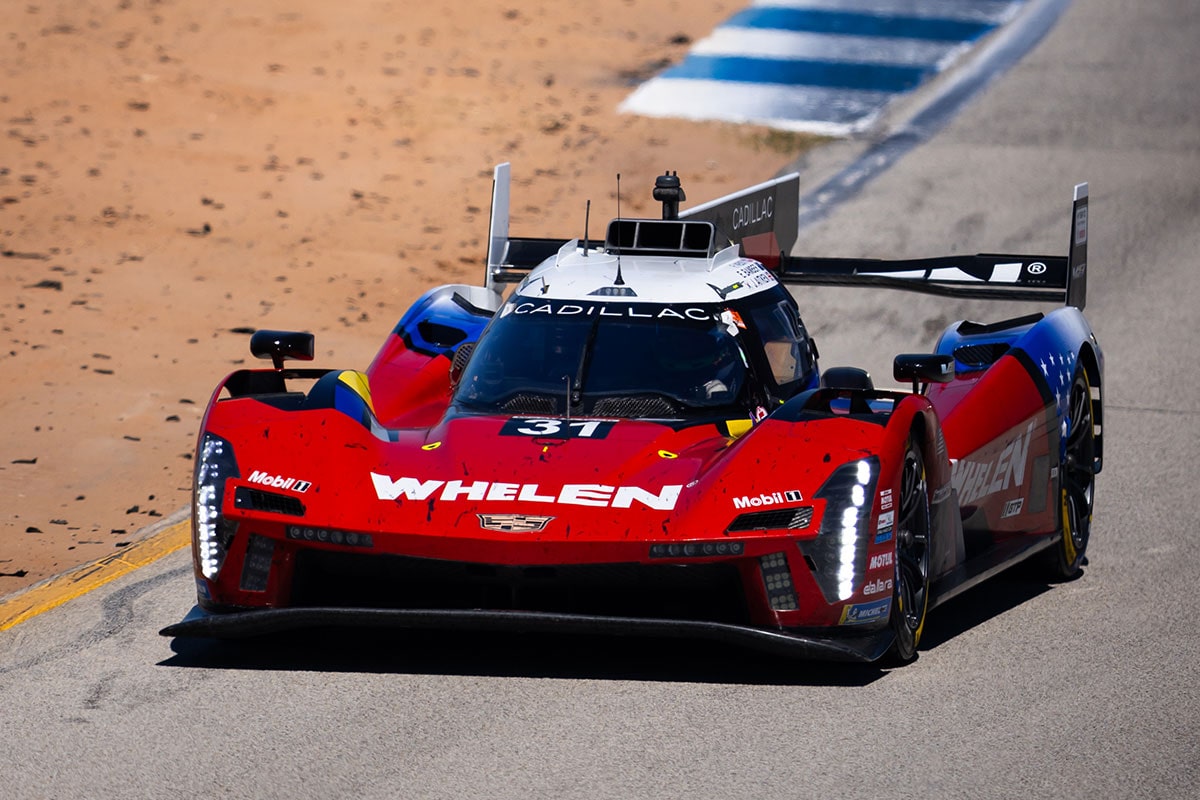 A Red Whelen Cadillac V-Series.R Race Car Speeds Down the Track at Night With Its Headlights Glowing and Motion Blur Emphasizing Its High Velocity.