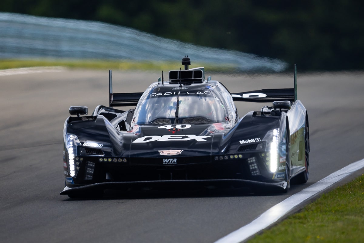 A Black Cadillac V-Series.R Race Car Navigating a Curved Track at Watkins Glen International Under Bright Daylight.