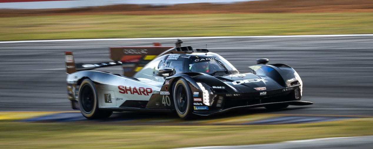 The No. 40 Black Cadillac V-Series.R Race Car Speeding on a Racetrack with Illuminated Vertical Headlights On