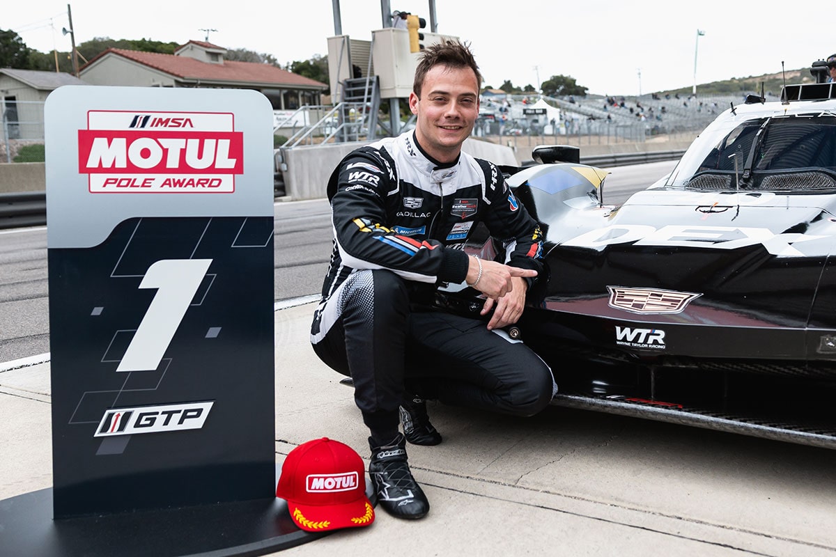 Close-up of a Cadillac Racecar Driver Wearing a Helmet Standing Next to a Racecar with the Butterfly Door Open