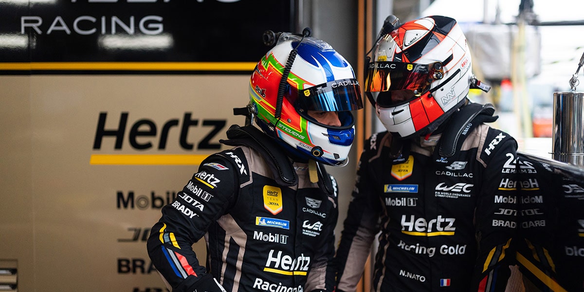 Close-up of Two Cadillac Racecar Drivers Wearing Their Helmets and Talking to Each Other