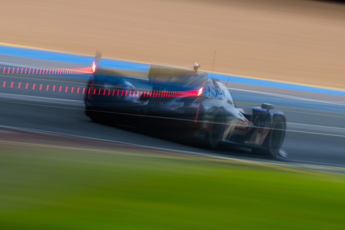 Blurry, Transparent View of a Cadillac Race Car Speeding Down a Track