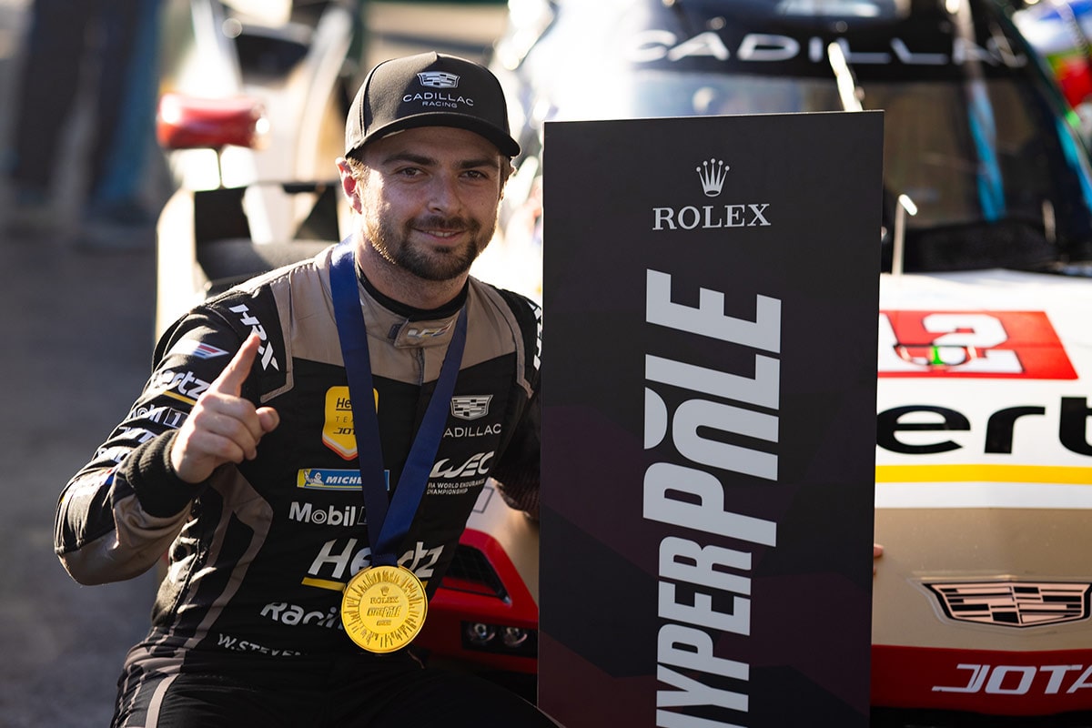 Person Wearing Cadillac Racing Apparel Holding a Rolex Hyperpole Medal in Front of a Cadillac Hertz Team JOTA Race Car.