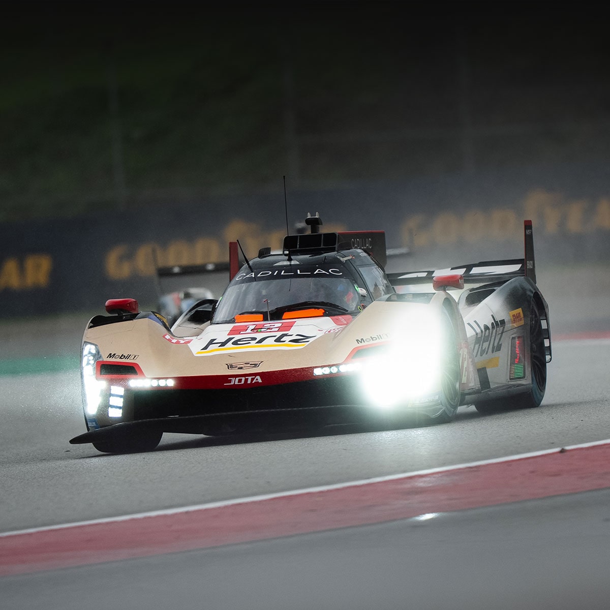 The No.38 Gold Cadillac V-Series.R Race Car Driving on a Race Track with the Stadium in the Background