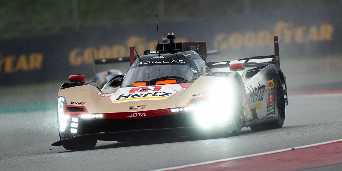 A Cadillac V-Series.R Race Car Driving Through Heavy Rain With Bright Headlights Illuminating the Wet Racetrack