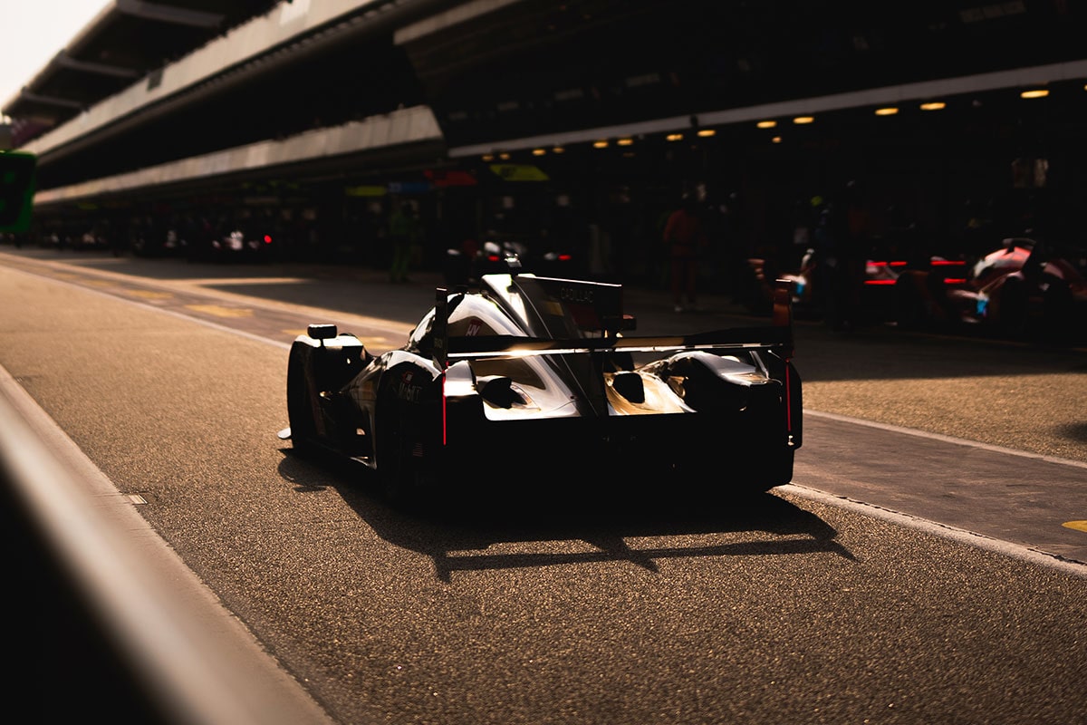 Close-up of a Cadillac Racing Driver Wearing a Reflective Racing Helmet and Cadillac Racing Team Uniform Standing in the Pit Lane
