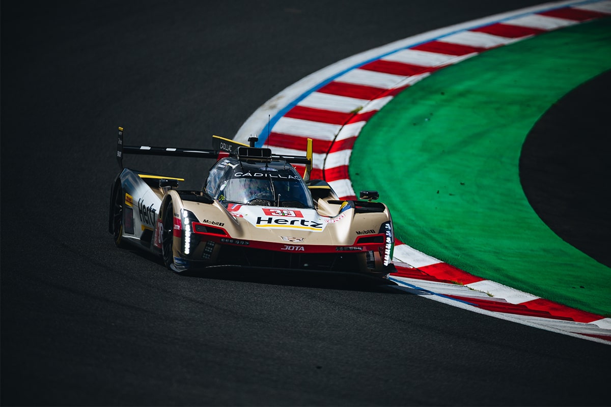 Three-quarter View of the Cadillac V-Series.R Hypercar Race Car Parked in Front of a Waving Texas Flag