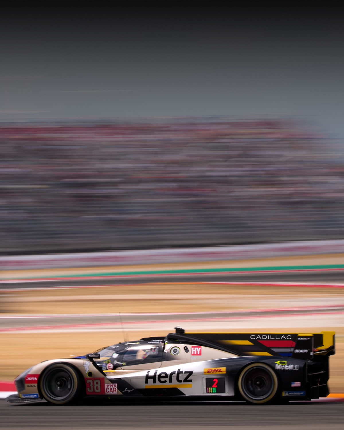 Cadillac Hertz Team JOTA Race Car Driving at Speed on a Racetrack With Motion Blur in the Background.