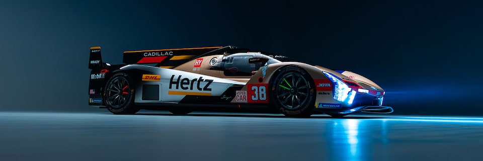 A Gold and Black Cadillac V-Series Race Car Number Thirty-Eight with Hertz Branding in a Studio with Blue Lighting
