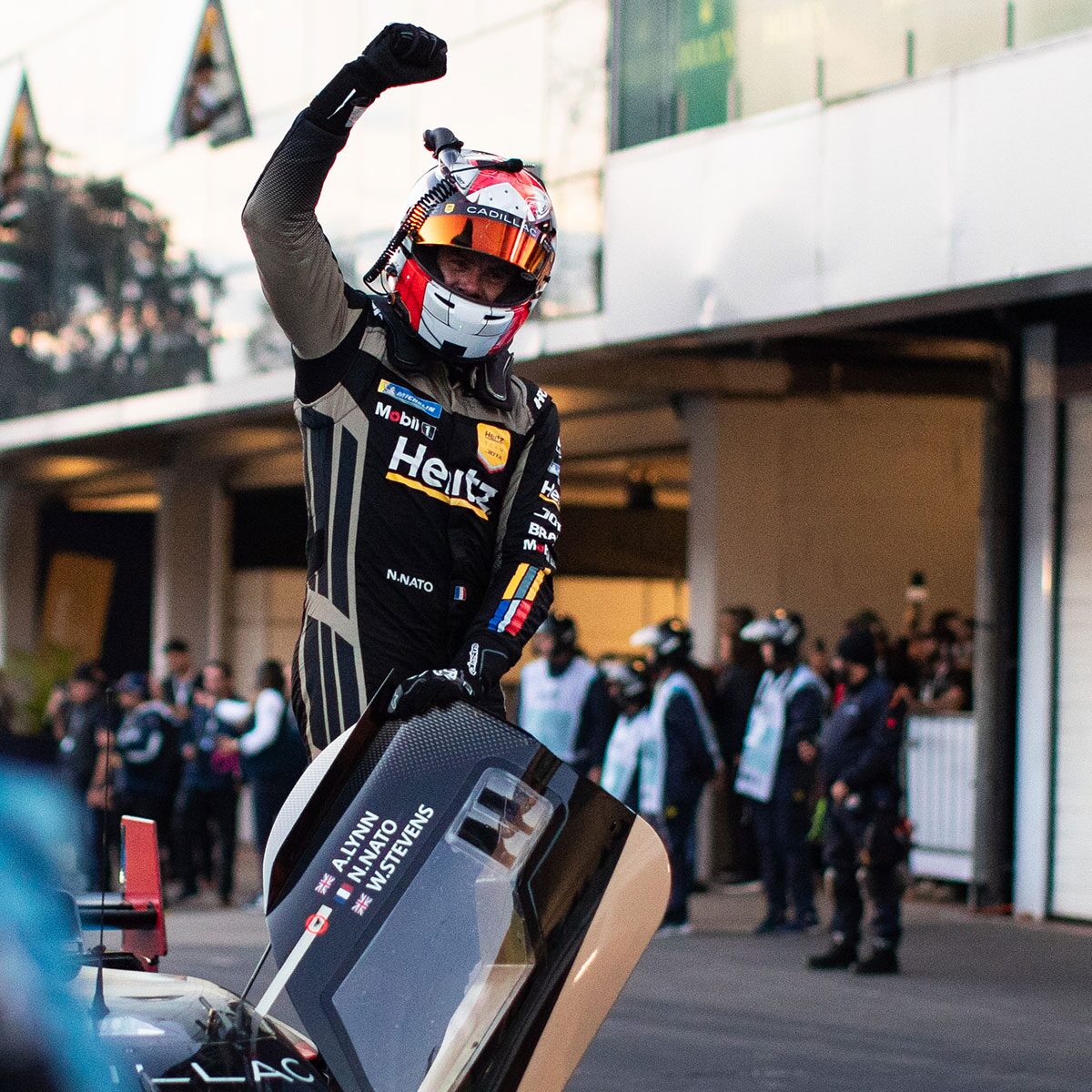 A Cadillac Race Car Driver Cheering While Getting Out of the His Race Car