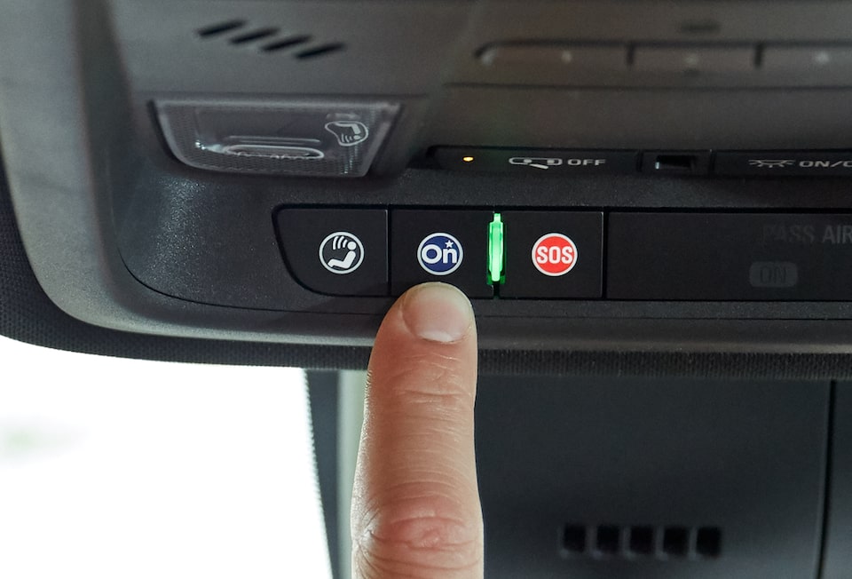 Driver Pressing OnStar Services Button in Cadillac Vehicle 
