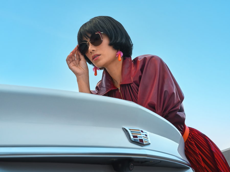 Women leaning against her Cadillac vehicle