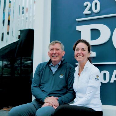 Couple sitting in front of the PGA Championship sign