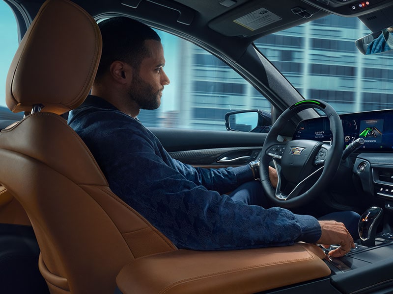 Passenger Side View of Man Driving a Cadillac Utilizing the Super Cruise Hands-free Technology