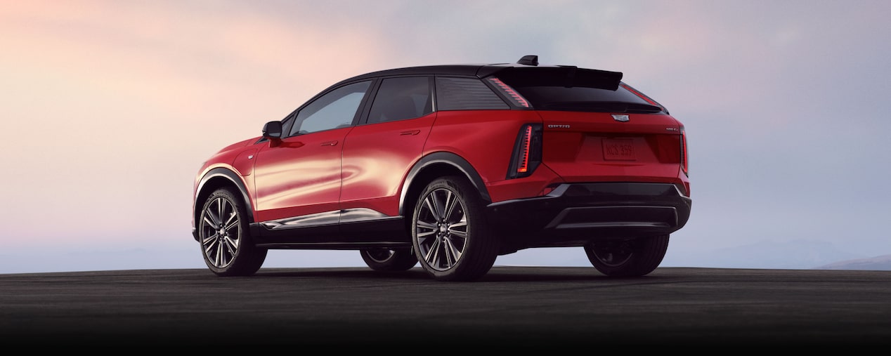 Rear Three-quarter View of a Red Cadillac OPTIQ EV SUV Outlooking a Beautiful Sky