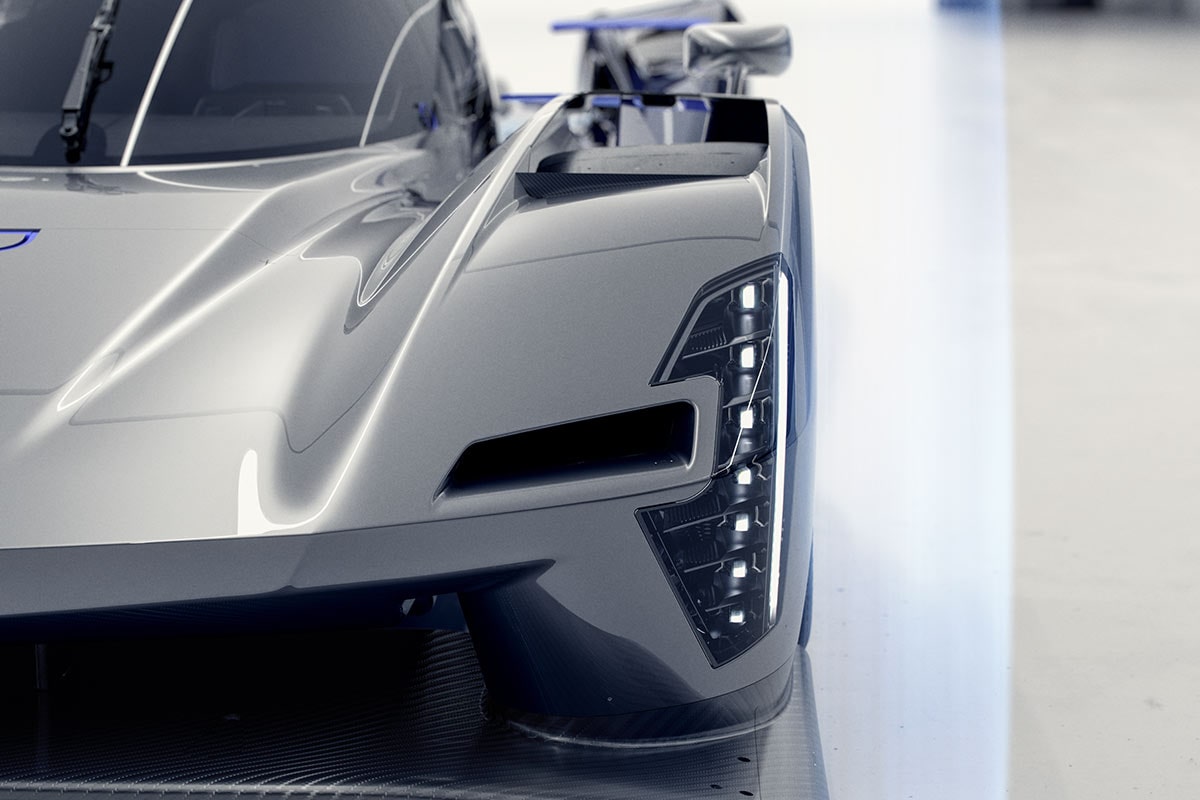 A Close-Up Front Corner View of the Silver Cadillac V-ONE Concept Vehicle Showcasing a Vertical LED Headlight, Sculpted Aerodynamic Bodywork, Carbon Fiber Front Splitter, and Rear Wing Inside a Bright White Studio.