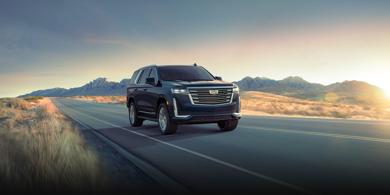 A Cadillac Escalade Driving On-Road during a Sunset