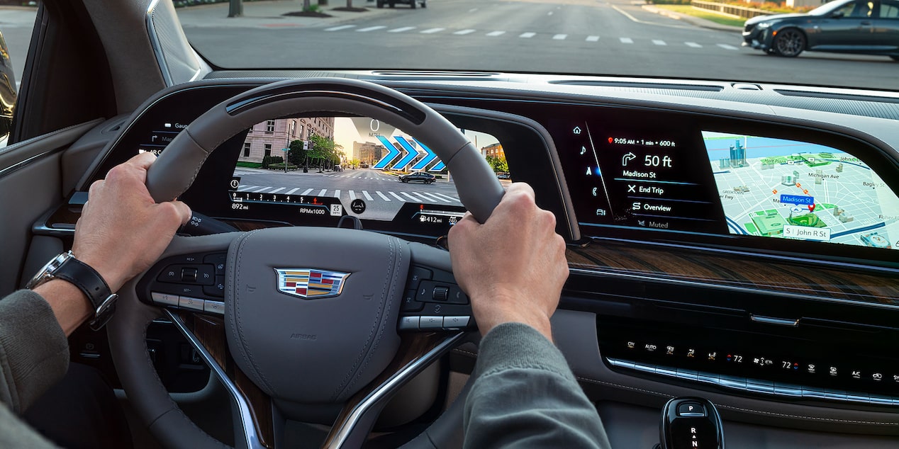 Man Driving his Cadillac Escalade While Using Navigation on the Infotainment System