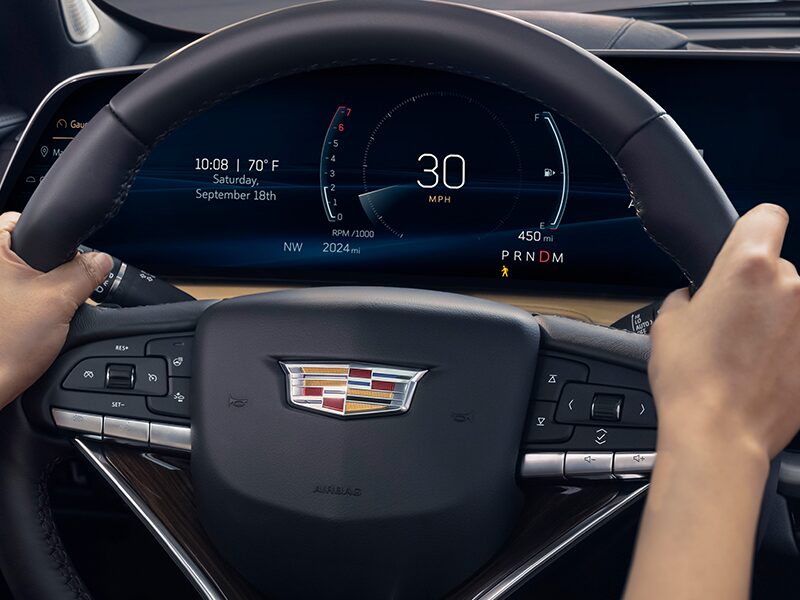 A Woman Uses Both Hands While She Drives Her Cadillac XT4 on a City Road