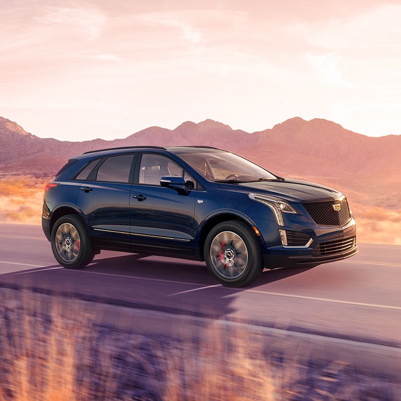 The 2024 Cadillac XT5 Driving Through a Western Landscape During Golden Hour