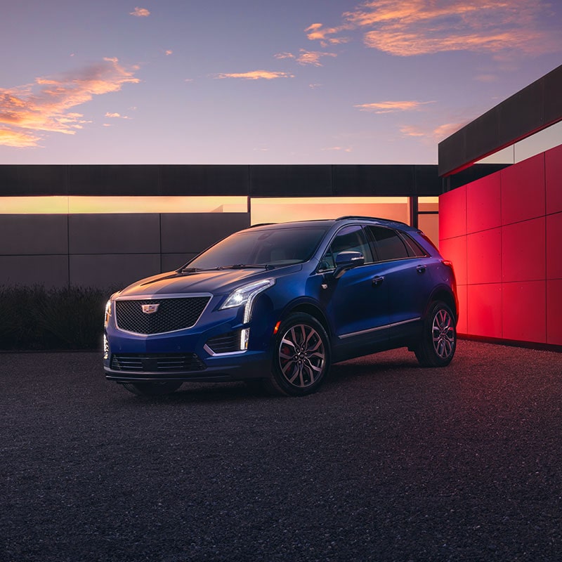 The Beautiful 2024 Cadillac XT5 Parked at Dusk in Front of a Modern House With Lights On
