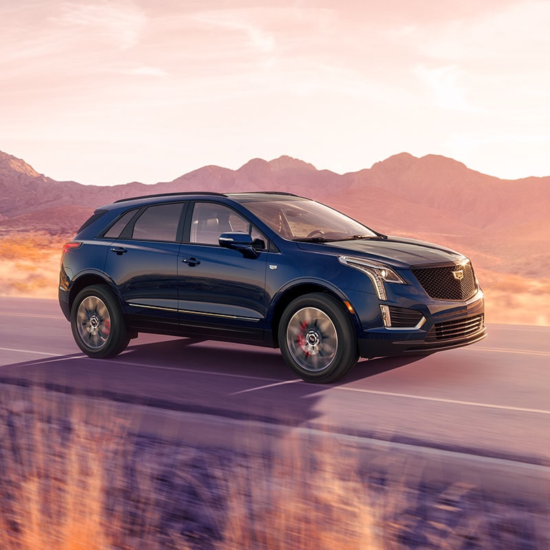 The 2024 Cadillac XT5 Driving Through a Western Landscape During Golden Hour