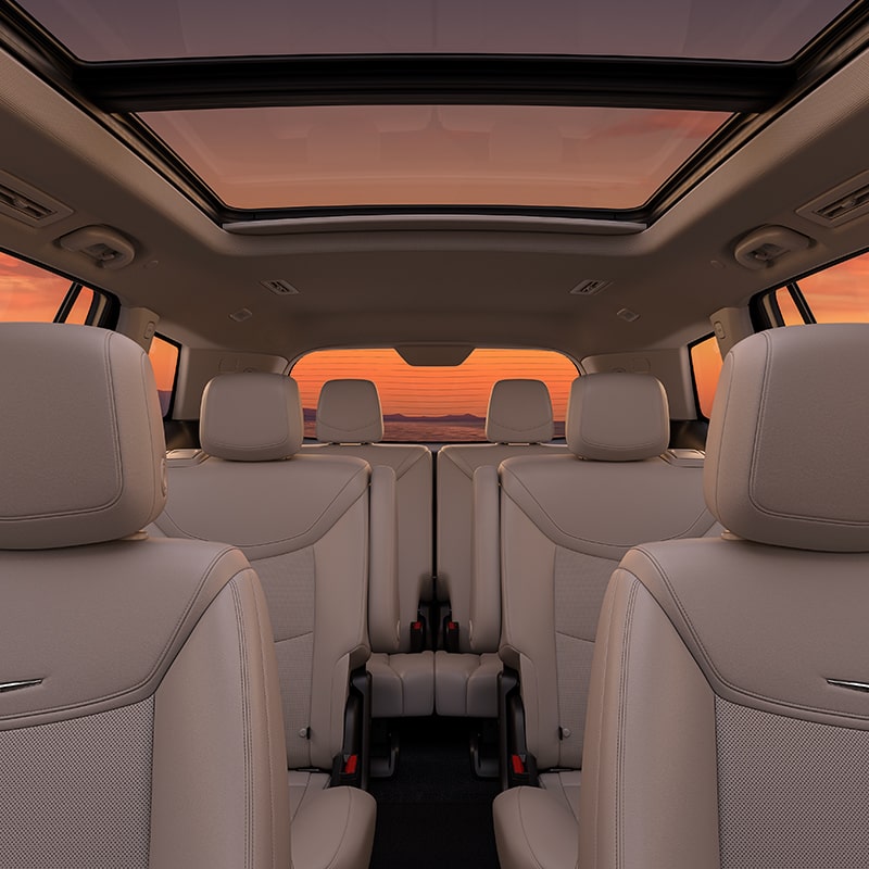 3 Rows of Tan Leather Seats Inside of the Cadillac XT6 Parked Under the Sunset